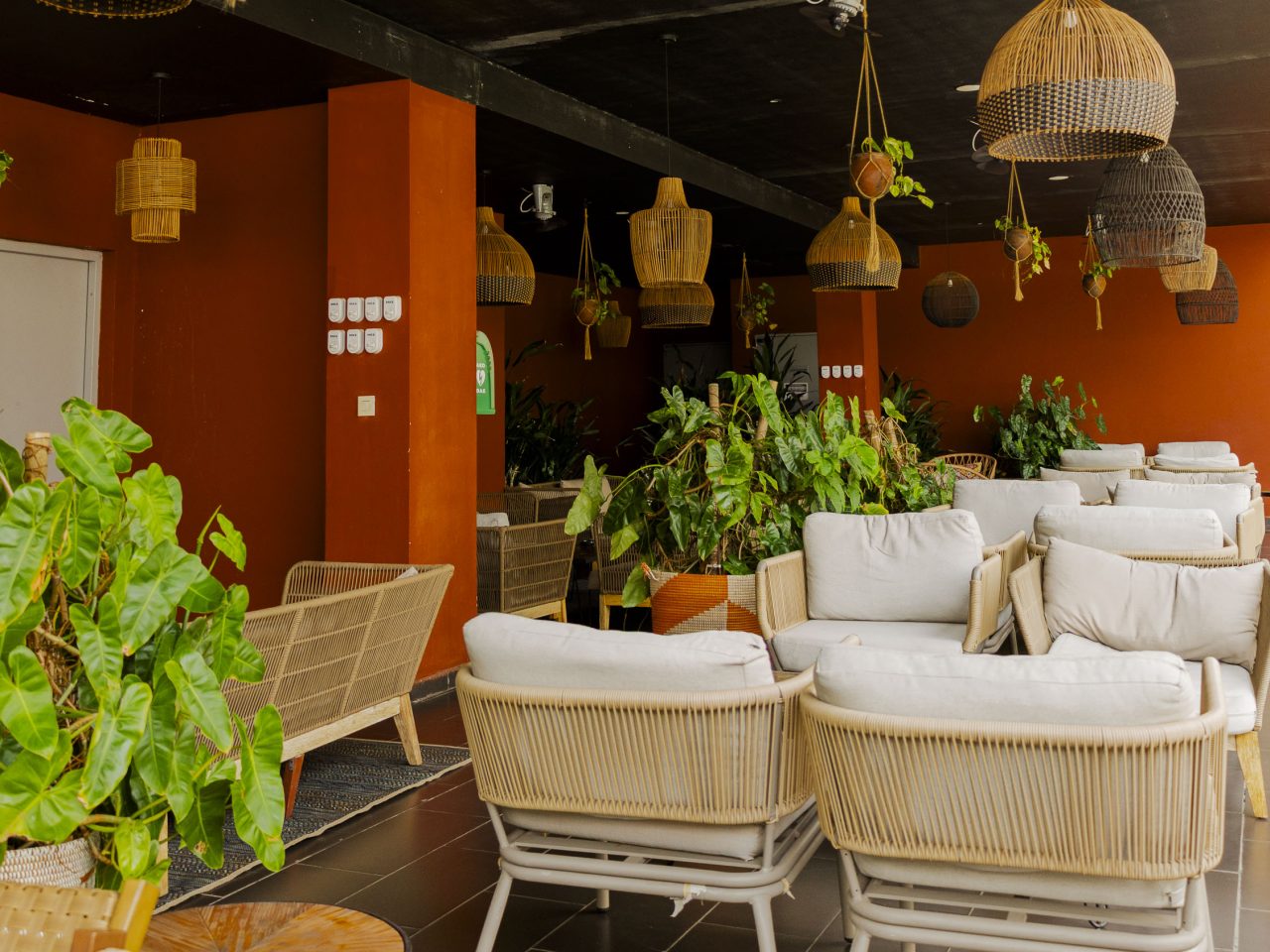 Le salon d'un hôtel de Conakry : suspensions en rotin, murs terre cuite et fauteuils en fibre tressée
